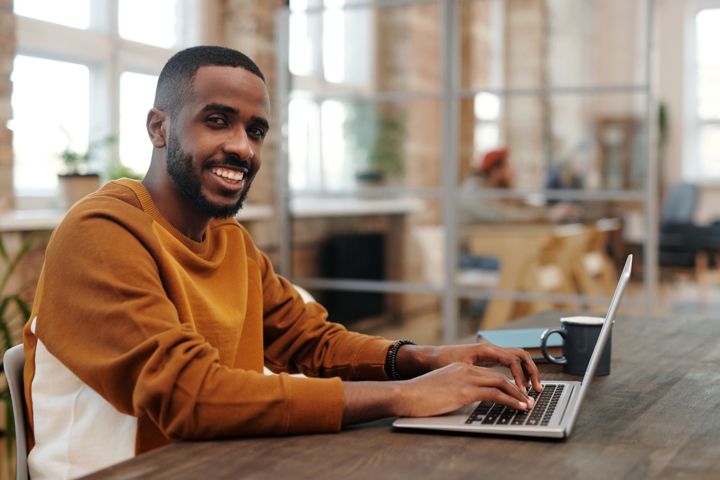 Jeune actif souriant devant son ordinateur portable